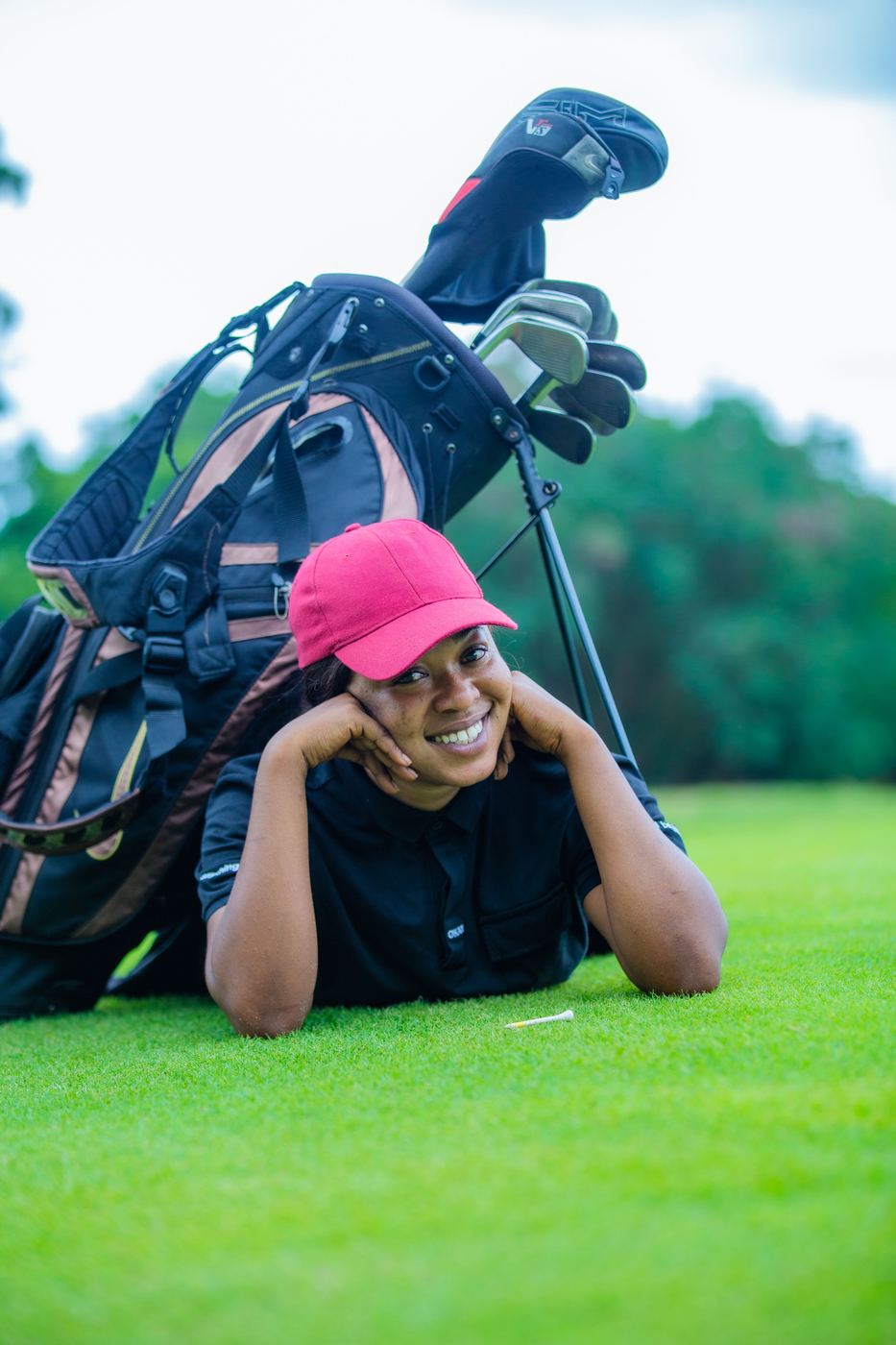Young golfer smiling on the fairway beside her bag
