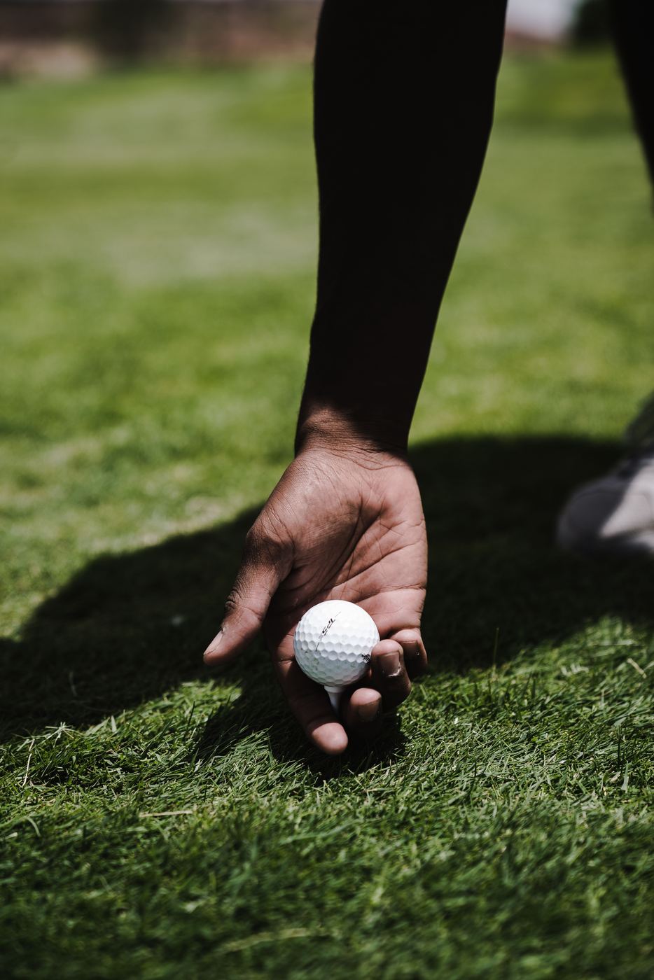 Hand placing a golf ball on the tee